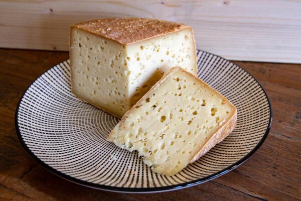 formaggio-di-pecora-stagionato-sette-mesi-forma-aperta-e-fetta-su-piatto-decorato